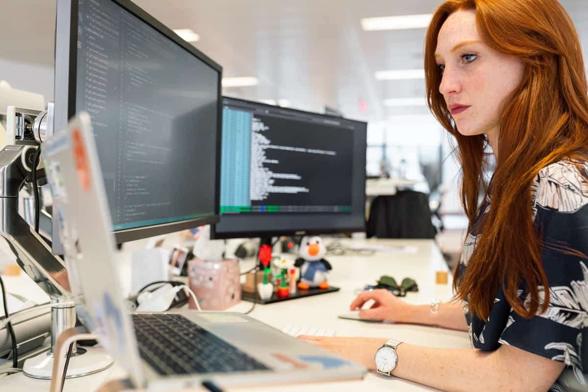 A woman coding on her computer at her workplace. Coding Bootcamps for Women