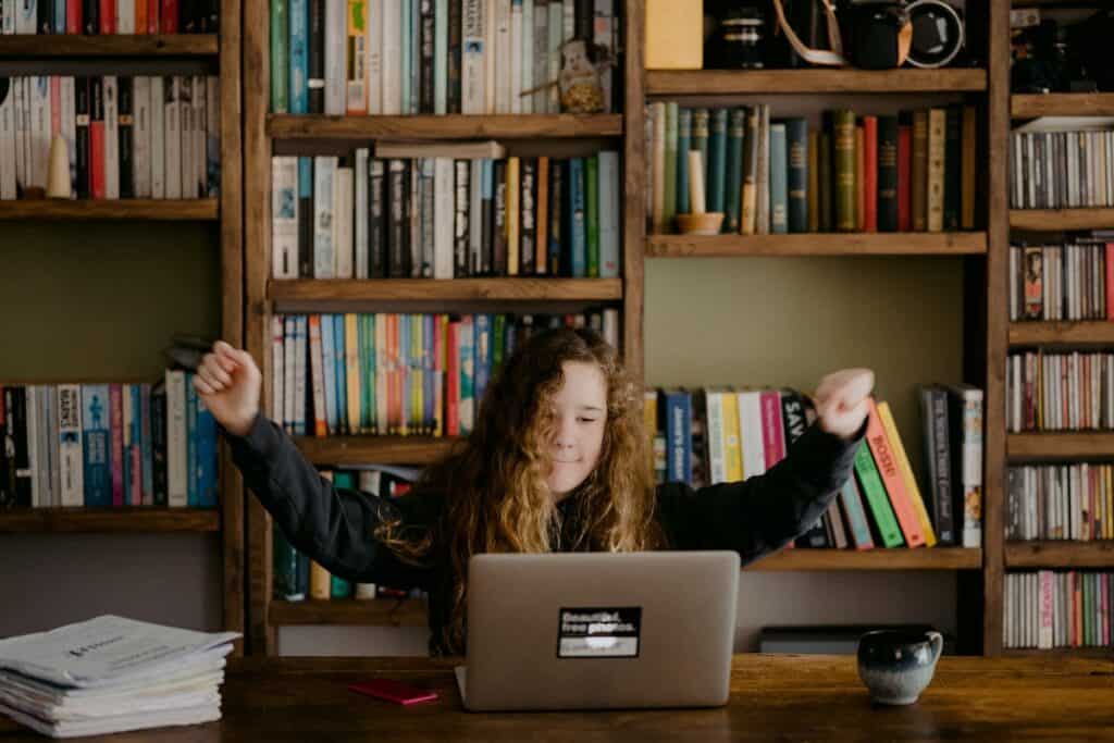 Girl spreading arms while looking at her laptop. How to Write a Great Resume