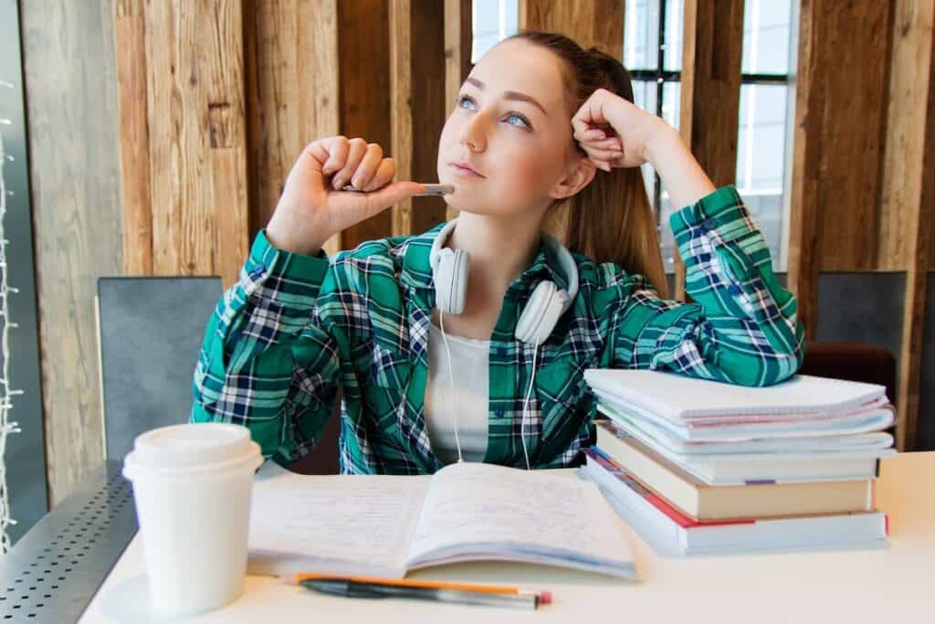 Student thinking in front of books and a coffee cup what is computer science