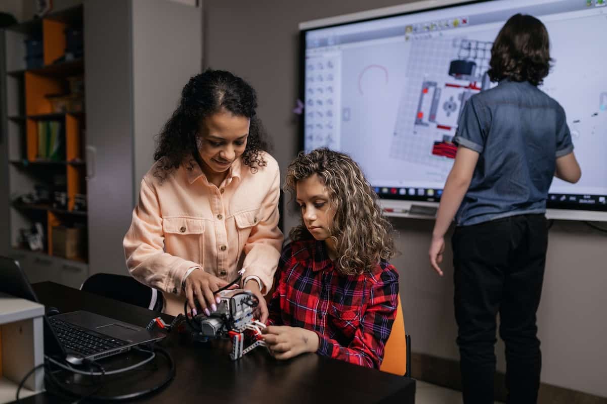 A teacher helping a student make a robot
